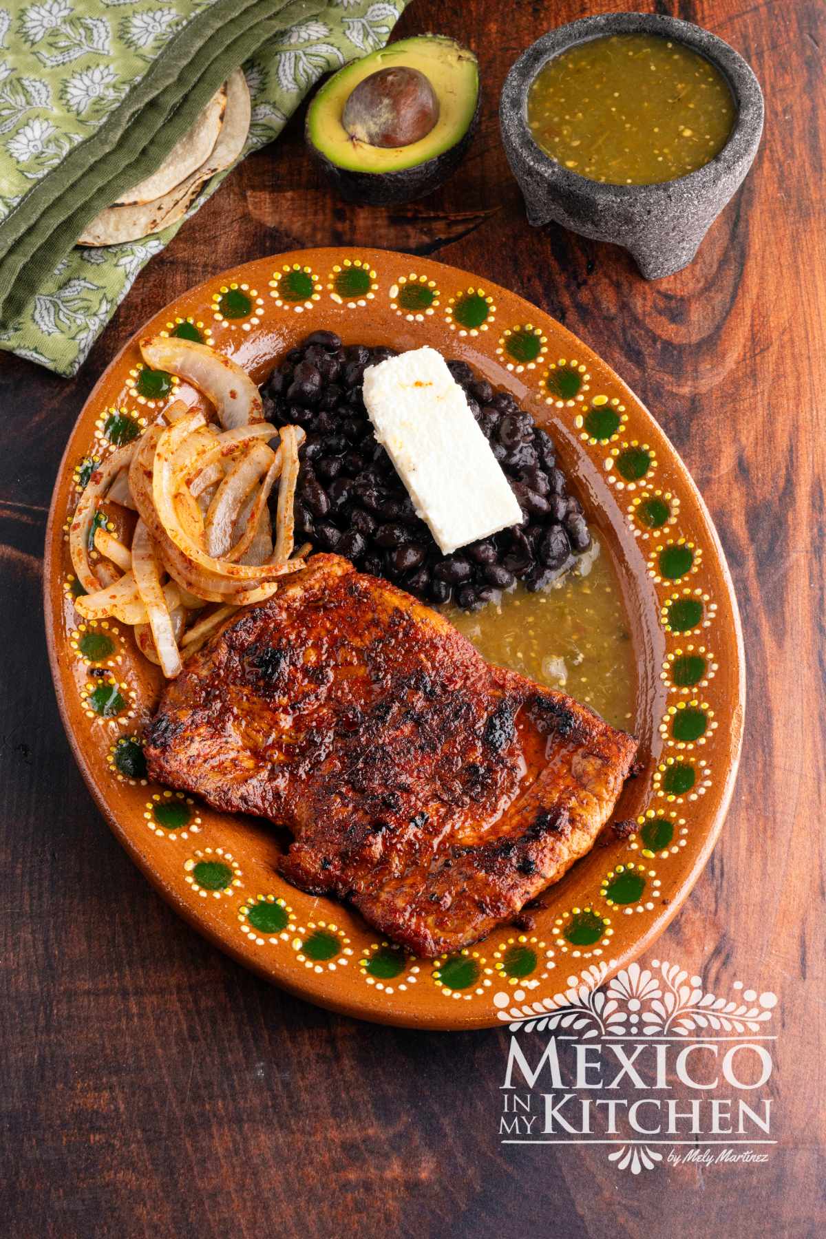 Carne enchilada serve in a platter with black beans, and queso fresco.