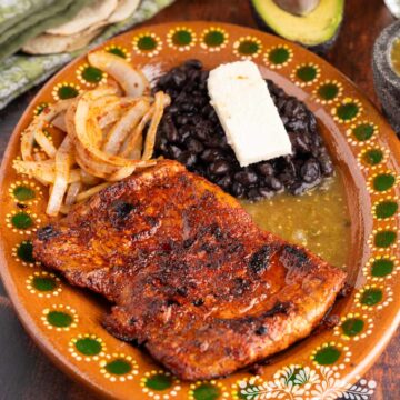 Carne enchilada serve in a platter with black beans, and queso fresco.