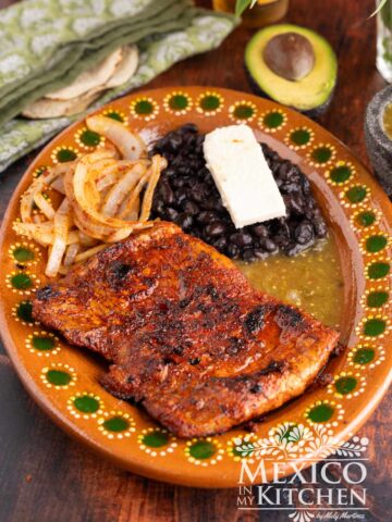 Carne enchilada serve in a platter with black beans, and queso fresco.