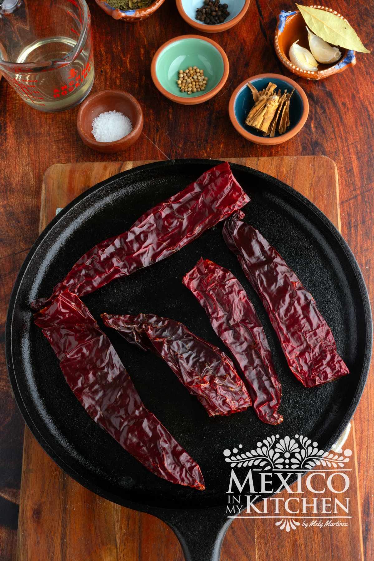 Toasting Guajillo peppers in a cast iron pan.