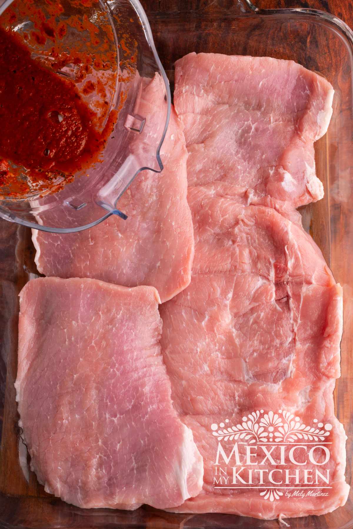 Pork steaks being marinated with guajillo sauce.