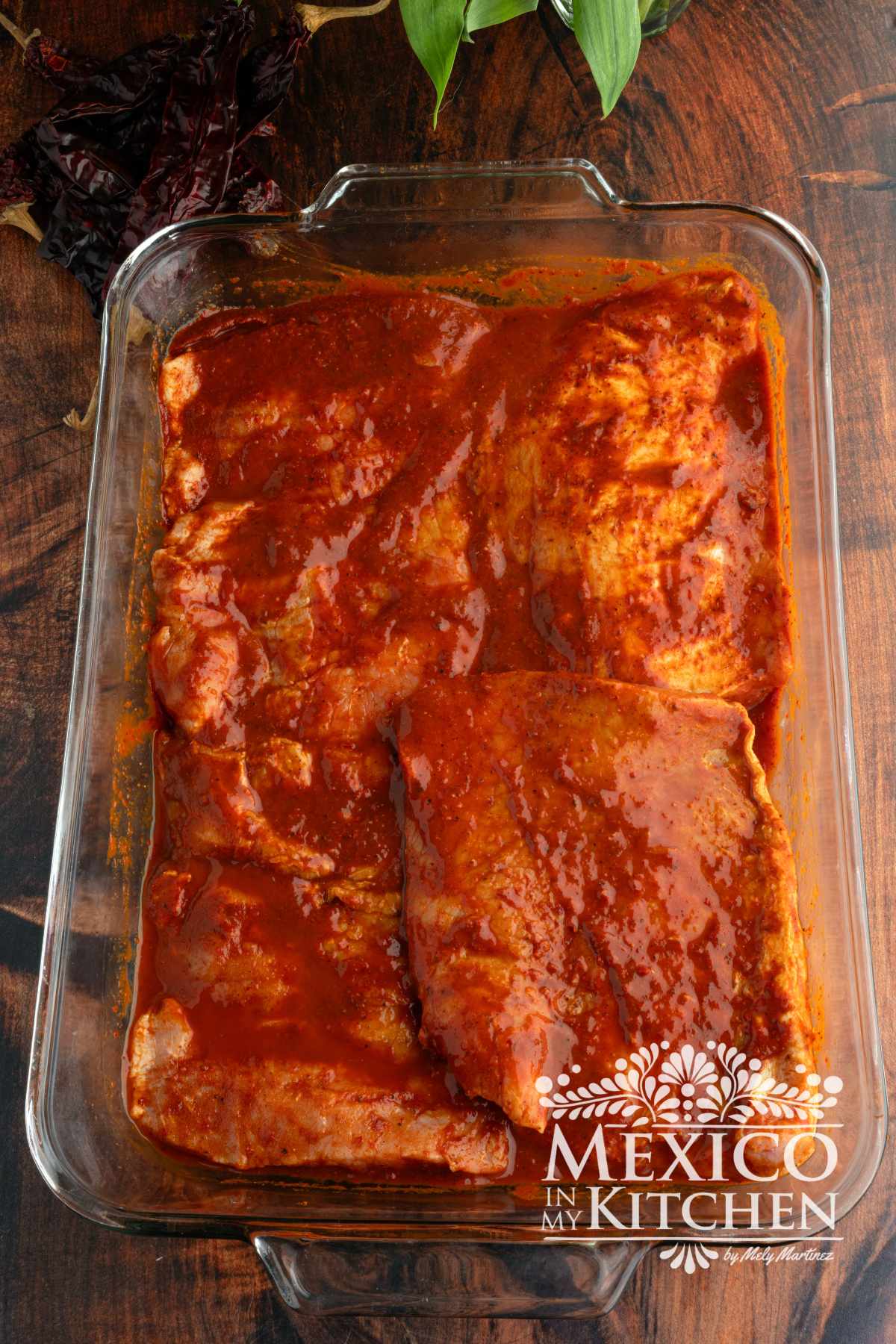 Pork steaks being marinated with guajillo sauce.