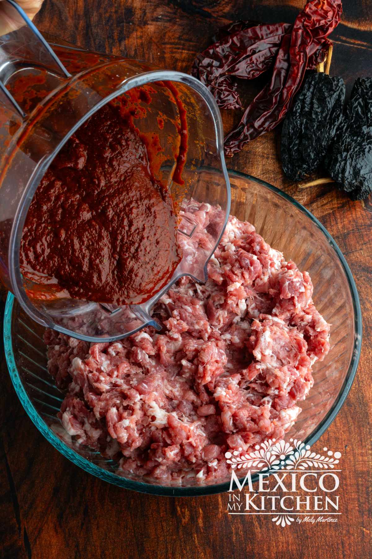Mixing peppers mix with the pork meat in a glass bowl.